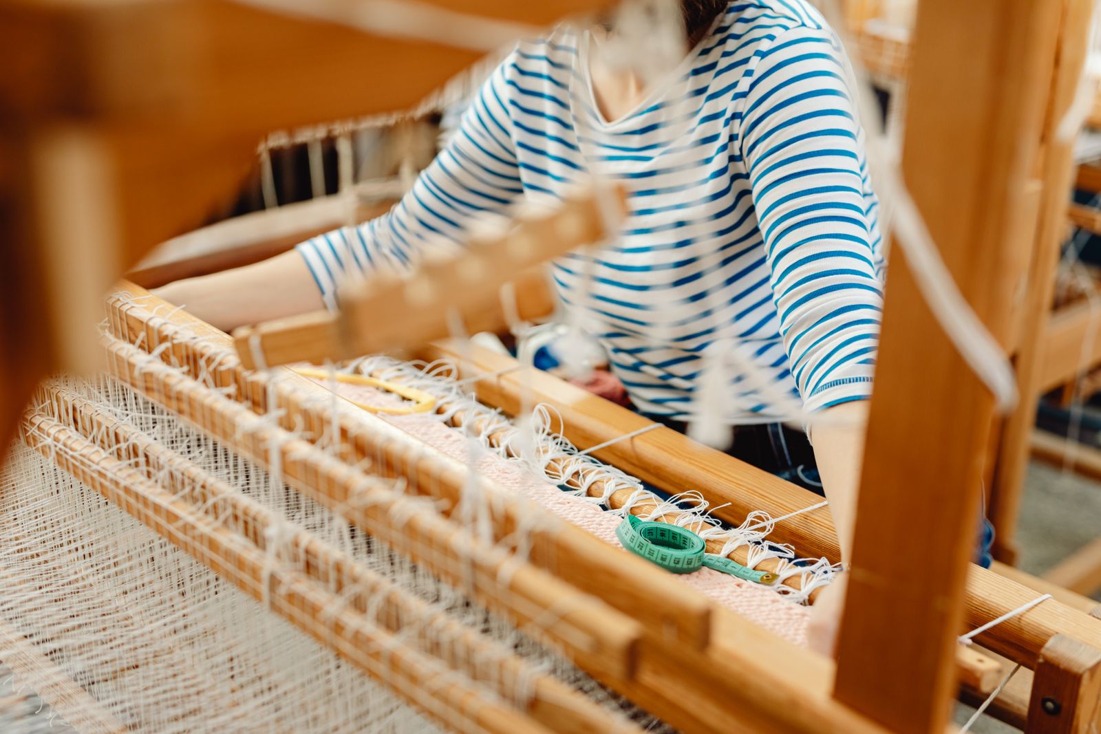 Finished wool batts and carded fiber preparation on a wooden surface, showing the flat continuous output of a drum carding session