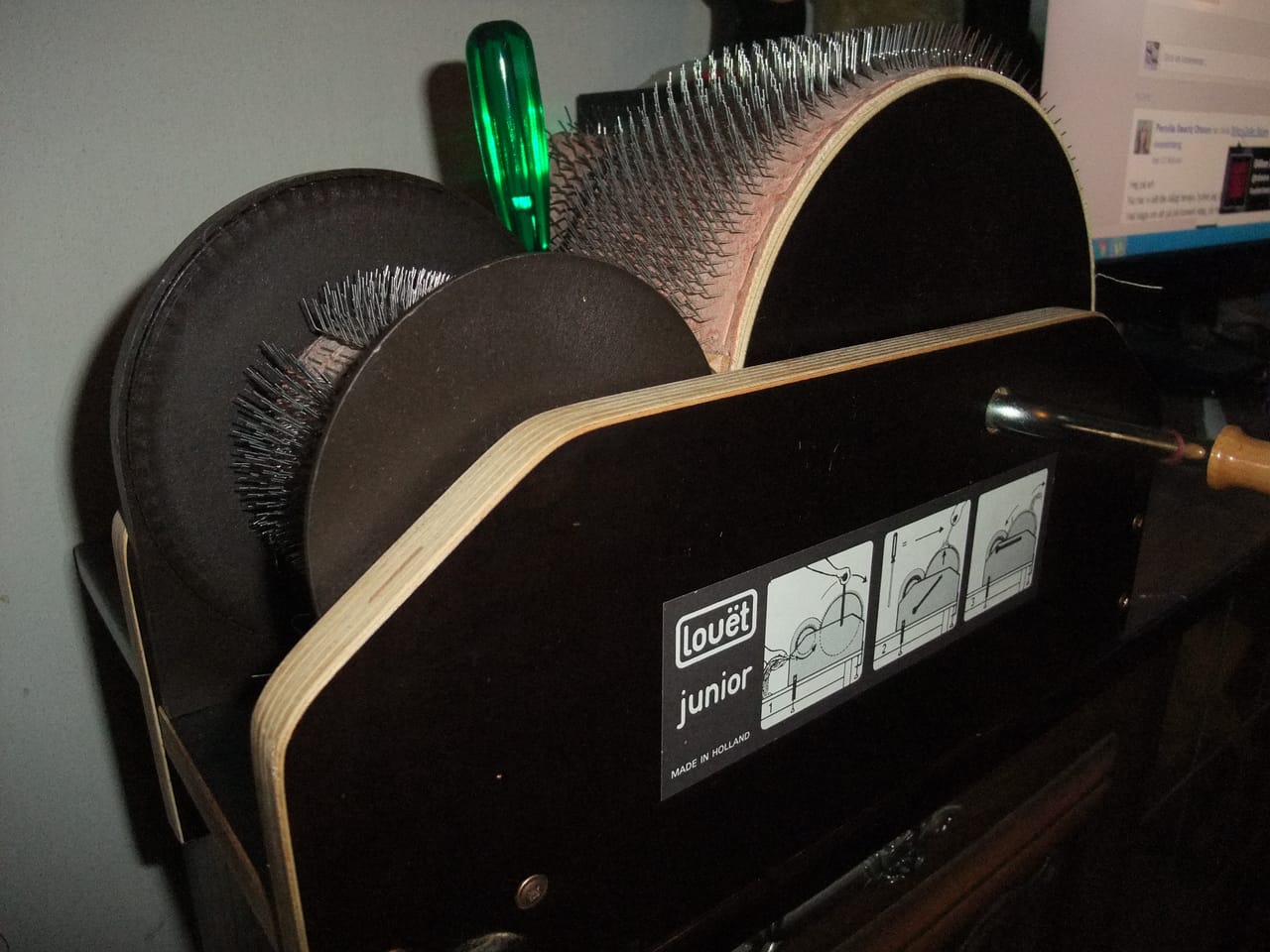 A wooden drum carder with two rollers covered in fine metal teeth, used for blending and carding raw wool fibers into batts for spinning