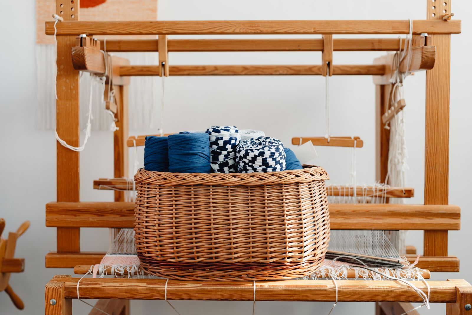 A weaver passing a stick shuttle through the open shed on a rigid heddle loom