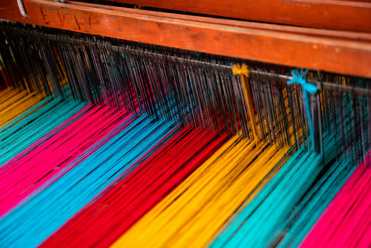Colorful woven textiles and fiber materials in a variety of hues, representing the range of projects and yarn types suitable for rigid heddle weaving