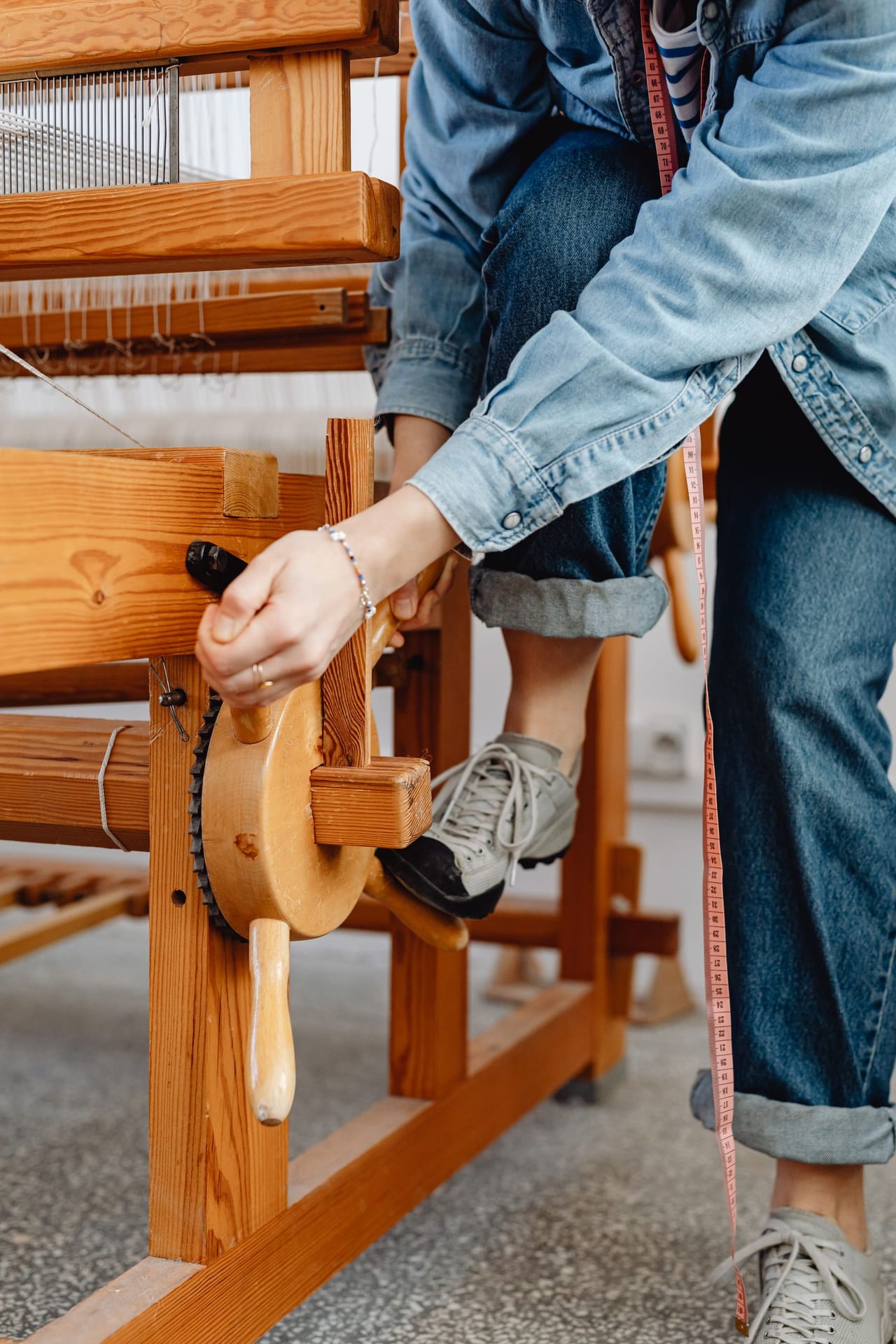 Close-up of warp and weft threads interlacing on a loom, showing the over-under plain weave structure forming cloth row by row