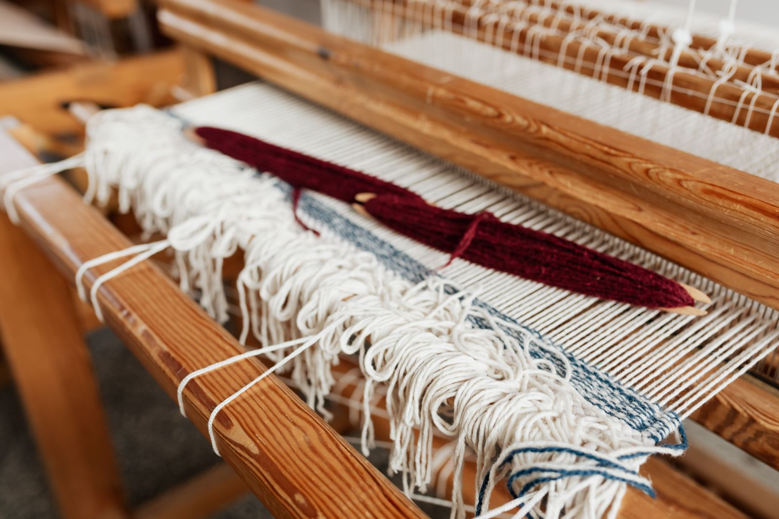 A Schacht Baby Wolf 4-shaft floor loom assembled in a home studio with natural light, showing the breast beam, beater, and treadles at the base