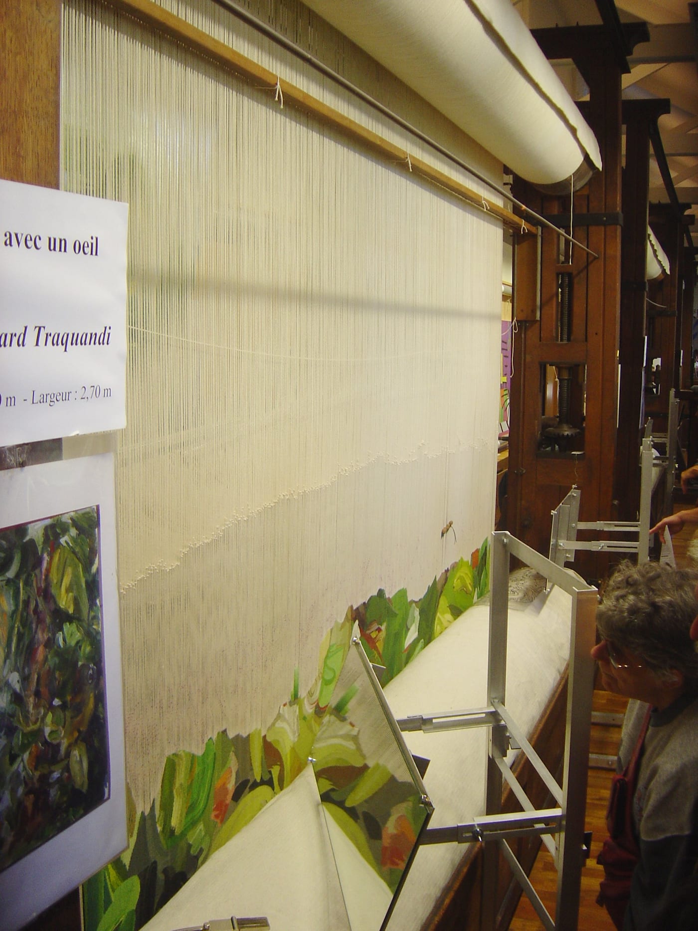 A tall vertical high-warp tapestry loom with warp threads under tension at the Gobelins manufacture in Paris