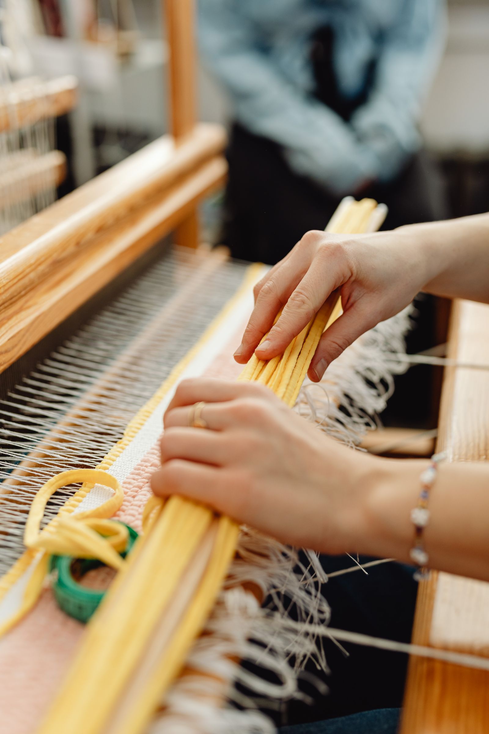 Close-up of a weaver passing colored weft through the warp on a tapestry loom